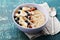 Bowl of homemade oatmeal porridge with banana, blueberries, almonds, coconut and caramel sauce on teal rustic table