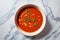 Bowl of hot tomato soup over marble background, top view photo. Italian food. Generative AI