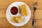 Bowl with ketchup, whole fried pancake roll, halves of pancake with meat in plate, fork on table. Top view