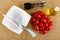 Bowl and knife, jar with condiment, heap of red tomato cherry, bottle with vegetable oil on mat. Top view