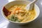 A bowl of laksa - a spicy noodle soup consisting of thick wheat noodles and seafood, popular in Southeast Asia.