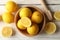 Bowl, lemons and wood juicer on background, top view