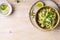 Bowl of linguine pasta with avocado sauce, green peas, zucchini, sprouts on rustic wood table