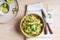 Bowl of linguine pasta with avocado sauce, green peas, zucchini, sprouts on rustic wood table