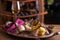 A bowl of mascarpone cheese in a spoon for ice cream on an old tray, next to a dish with blue cheese, bruno st, carambola fruits.