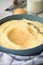 Bowl with mashed potatoes and ingredients as potato, milk, nutmeg with kitchen towel and grinder on light marble background