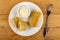 Bowl with mayonnaise, whole fried pancake roll, halves of pancake with meat in plate, fork on table. Top view