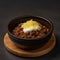 Bowl of Mexican food chili with cheese on black background