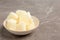 Bowl with milk ice cubes on grey table.