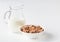 Bowl of multigrain natural flakes and milk jug on a white background. Healthy food. Side view.