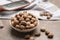 Bowl with nutmeg seeds on grey table, closeup