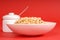 Bowl of oat cereal with sugar bowl on red background