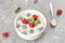 Bowl of oat granola with fresh raspberries, blueberries and mint for healthy breakfast, top view. Portion of cereal garnished