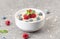 Bowl of oat granola with fresh raspberries, blueberries and mint for healthy breakfast, top view. Portion of cereal garnished