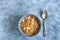 Bowl of oatmeal cereals breakfast with a silver spoon on a blue cement and concrete background, table setting