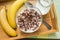 Bowl of oatmeal chocolate flakes in the shape of letters of the alphabet with milk on a wooden tray with bananas and a jug of milk