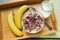 Bowl of oatmeal chocolate flakes in the shape of letters of the alphabet with milk on a wooden tray with bananas and a jug of milk