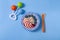 Bowl with oatmeal , raw , for a child, with apple slices and blueberies,  top view on a blue background