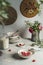 Bowl with oats porridge and raspberries heart on grey table with kitchen utensils, flower bunch, stapled bowls and home decoration