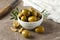 Bowl with olives, leaves, knife and towel on background, close up