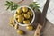 Bowl with olives, leaves, knife and towel on background, top view