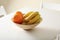 Bowl with oranges and bananas on white table