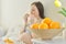 Bowl with oranges in focus, pregnant young woman eating slices of oranges sitting in bed