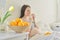 Bowl with oranges in focus, pregnant young woman eating slices of oranges sitting in bed