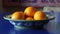 a bowl of oranges sitting on a blue counter top with a painting in the backgrouf of the bowl behind it and a blue table