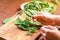 Bowl overfilled with spinach.Female hands sorting fresh spinach for use in a salad on a wooden background. Salad with