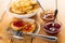 Bowl with pancakes, saucer of fried pancakes with jam, fork, bowls with jams on wooden table