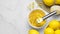 Bowl with peel pieces, fresh lemons and zester on white marble table, flat lay. Space for text