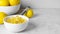 Bowl with peel pieces, fresh lemons and zester on white marble table. Space for text