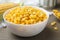 Bowl of preserved corn on wooden table, closeup