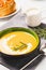 Bowl of pumpkin cream soup with garlic buns and heavy cream. Thick butternut squash bisque in green bowl