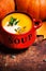 Bowl of pumpkin soup swirled with coconut cream with fresh pumpkins and bread crouton on wooden table.