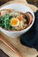 A bowl of ramen with a fried egg and green vegetables