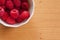Bowl of Raspberries on a wooden table.