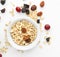 Bowl with raw oatmeal, raisins and cranberries on white background