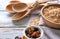 Bowl with raw oatmeal, raisins and spoons on wooden background