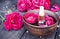 Bowl with red rose petals on a background of dark wooden boards and essential oil with roses