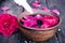 Bowl with red rose petals on a background of dark wooden boards and essential oil with roses