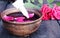 Bowl with red rose petals on a background of dark wooden boards and essential oil with roses