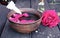 Bowl with red rose petals on a background of dark wooden boards and essential oil with roses