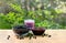 Bowl with ripe berries wild bilberries, bowl with jam of bilberries and of fruit yogurt on wooden table on background of shrubs