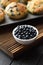 Bowl of ripe wild bilberries and freshly baked muffins on oak cutting board copy space. Low key still life with natural lighting