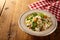 Bowl of risotto risi bisi and veggies beside checkered napkin