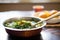 bowl of saag aloo with steam rising, spoon on side