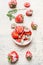 Bowl with sliced strawberries sprinkle with powdered sugar on white wooden background