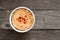Bowl of spicy hummus, above view on rustic wood
